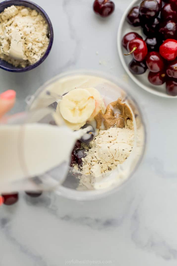 milk being poured into blender with smoothie ingredients