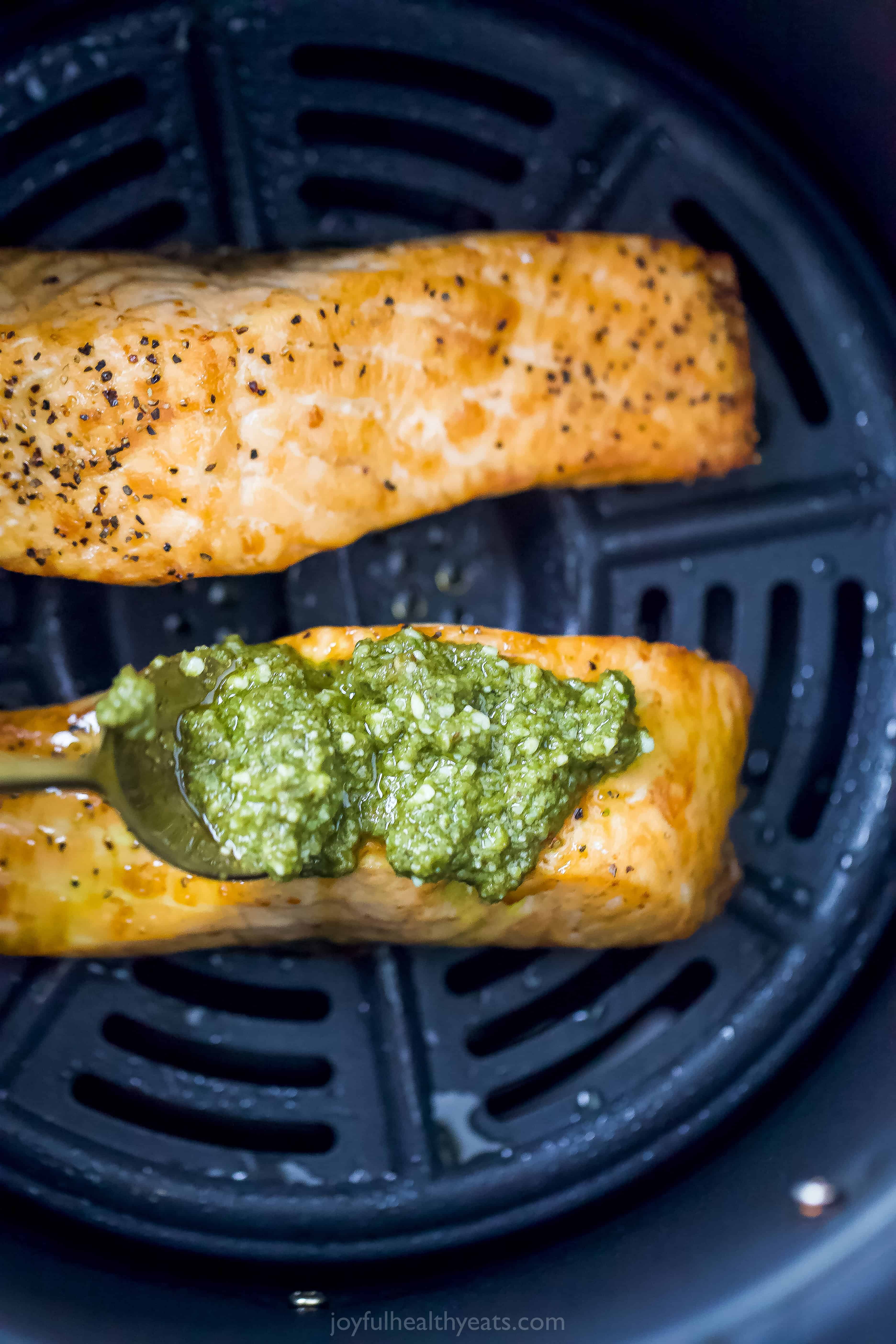 pesto being spread on salmon in air fryer