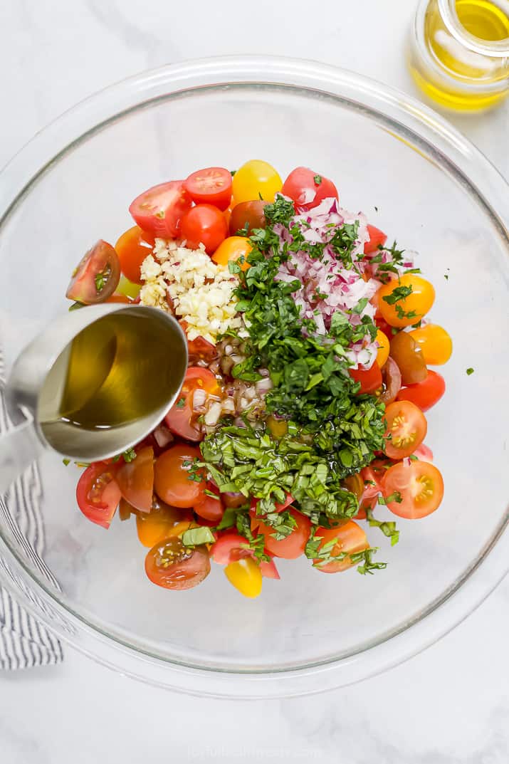 pouring marinade over tomato salad