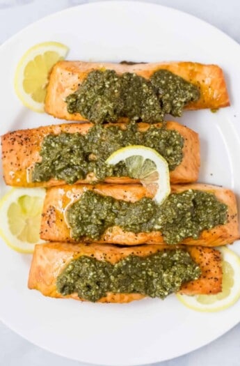salmon filets on a plate topped with basil pesto