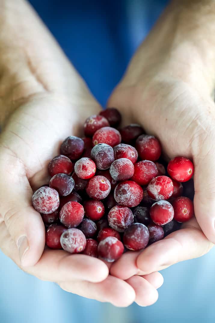 hands holding a bunch of frozen cranberries