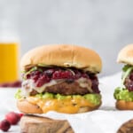 avocado turkey burger topped with cranberry chutney on a cutting board