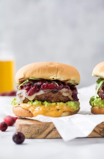 avocado turkey burger topped with cranberry chutney on a cutting board