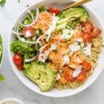 A buffalo chicken quinoa bowl on a marble counter photographed from above