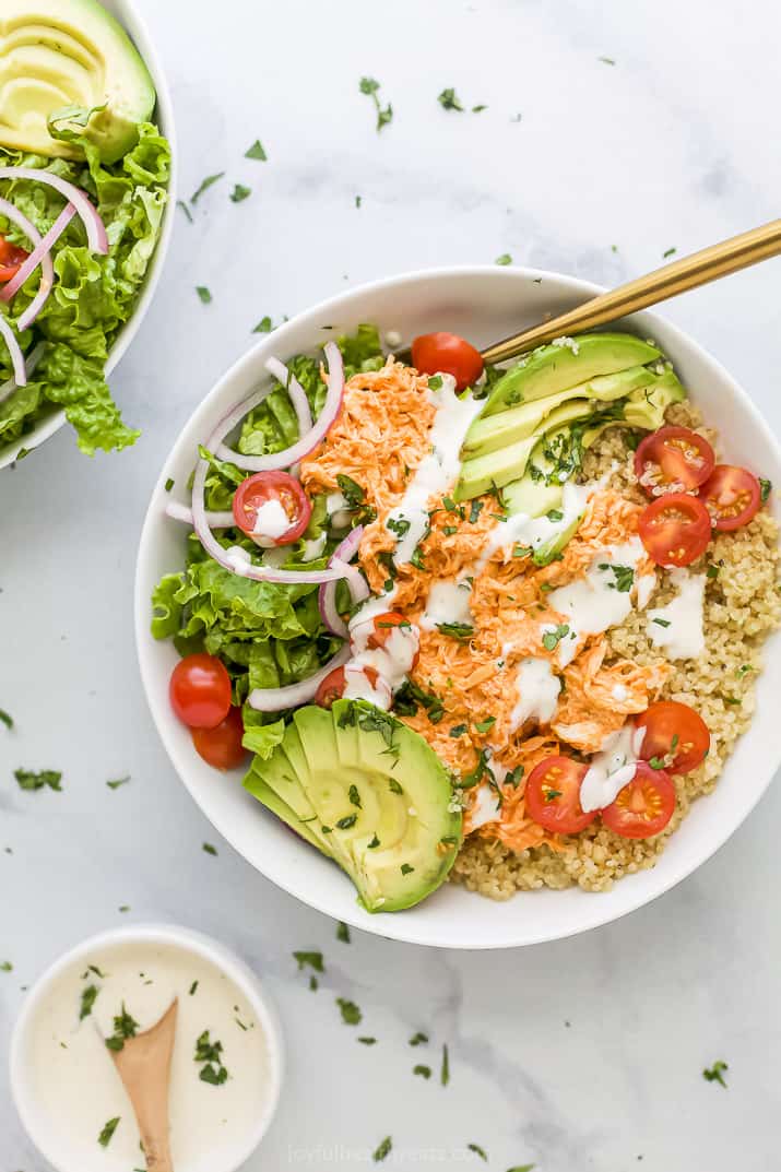 A buffalo chicken bowl on a counter full of small bits of chopped cilantro