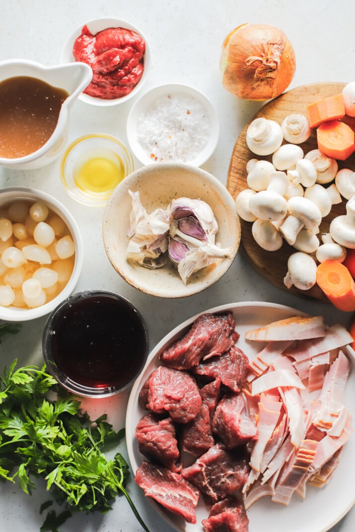 Sliced beef, carrots, mushrooms and the rest of the ingredients arranged on a white countertop