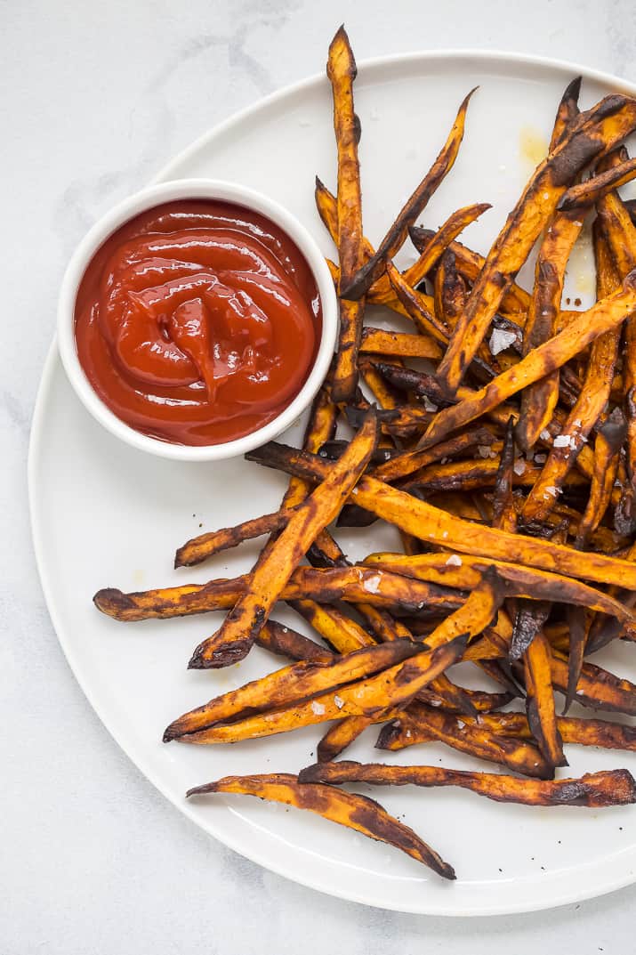 Air fryer sweet potato fries on a plate with ketchup.