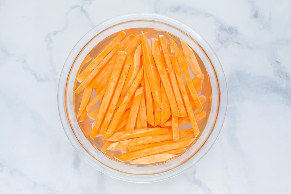 Sweet potato fries in a bowl of water.