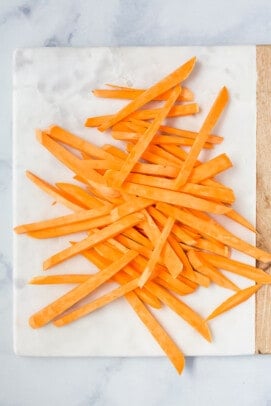 Sliced sweet potato fries on a cutting board.