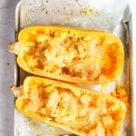 Cooked spaghetti squash on a lined baking sheet with a metal fork