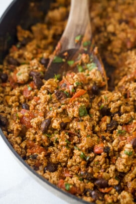 A close-up shot of the poblano filling in a skillet being mixed with a wooden spoon