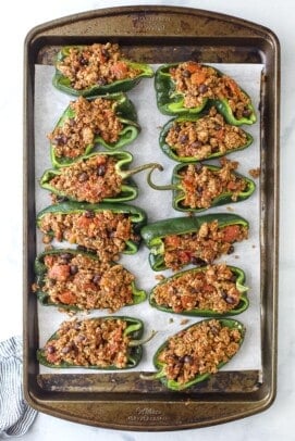 Twelve ground turkey stuffed poblano peppers lined up on a metal baking sheet