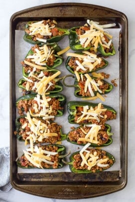 The stuffed and cooked poblano peppers with shredded cheese sprinkled on top befire it has been melted