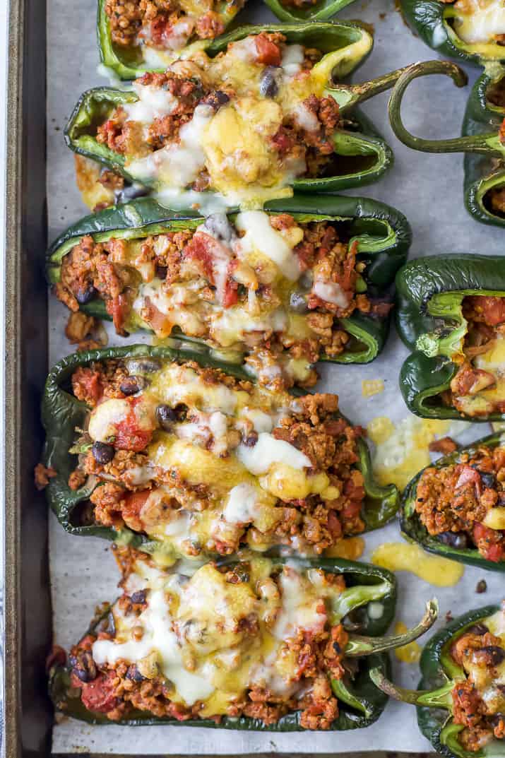 A close-up shot of turkey stuffed poblanos on a baking sheet lined with parchment paper