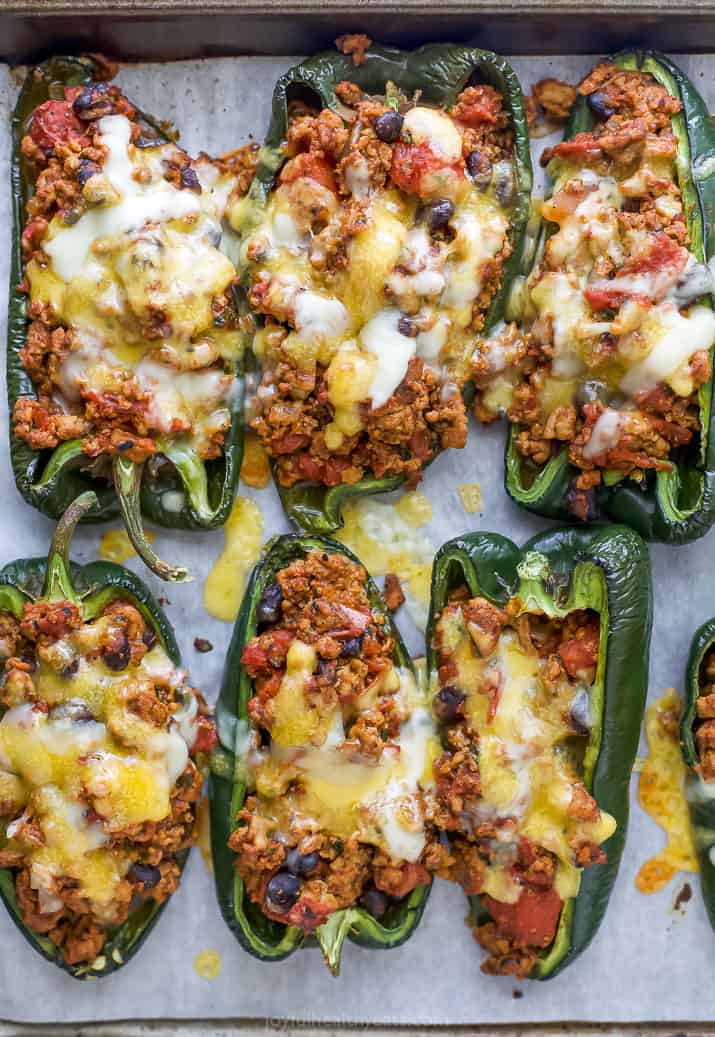Six turkey stuffed poblano pepper halves on top of a lined baking sheet