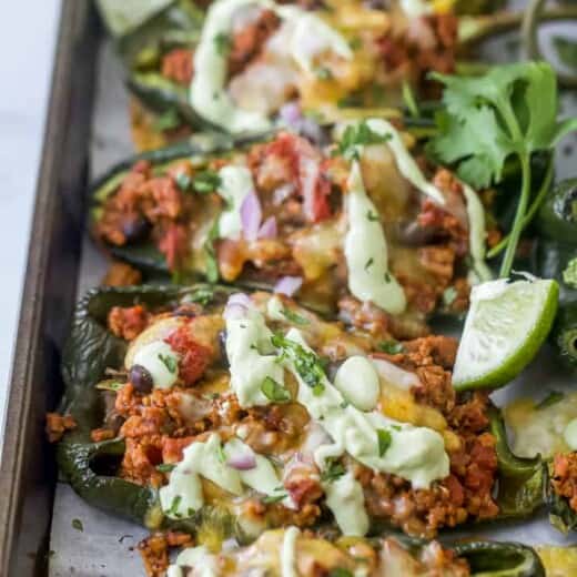 Turkey stuffed peppers on a lined baking sheet with avocado crema drizzled on top