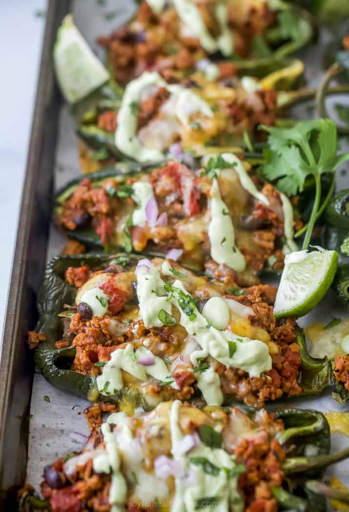 Turkey stuffed peppers on a lined baking sheet with avocado crema drizzled on top