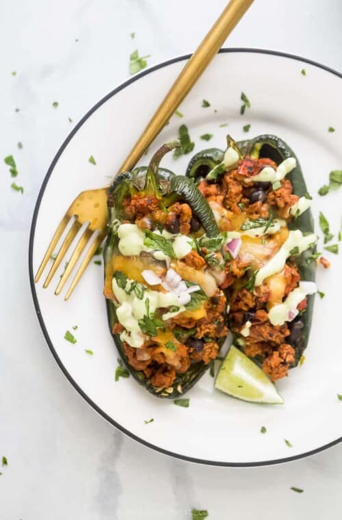 A turkey stuffed poblano pepper on a white plate with a golden fork