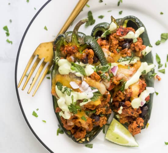 A turkey stuffed poblano pepper on a white plate with a golden fork