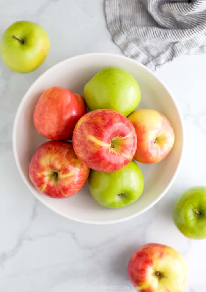 A bowl of Granny Smith and Honey Crisp apples on a marble countertop