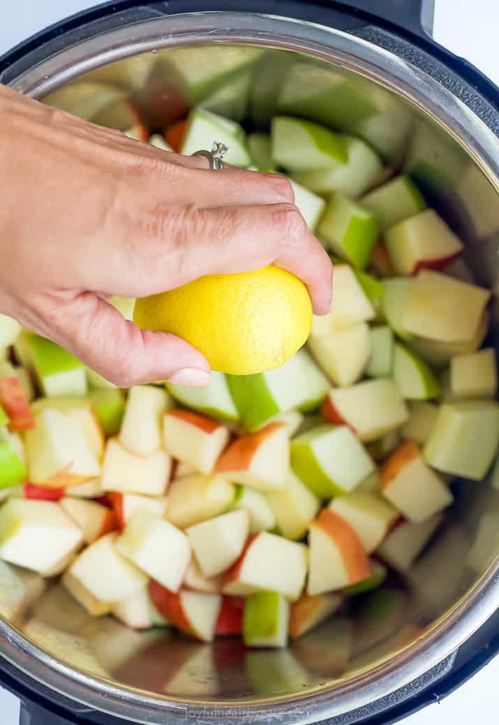 A lemon being squeezed over an Instant Pot filled with chopped apples