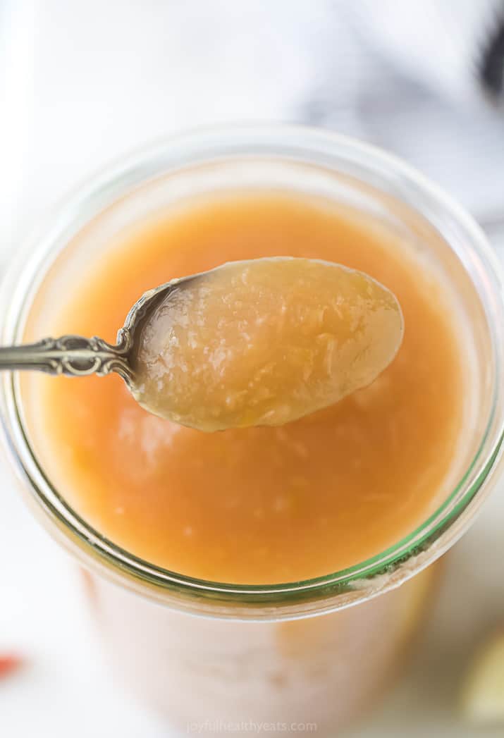 A full spoon hovering over a jar filled with Instant Pot applesauce