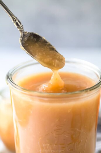 A close-up shot of a spoon lifting some unsweetened applesauce out of a glass