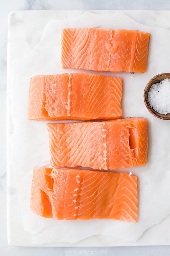 Uncooked salmon filets on parchment paper.