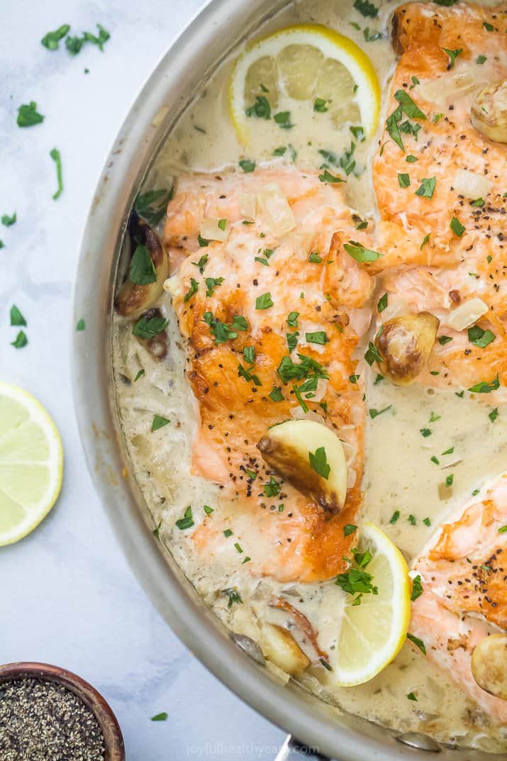 Salmon in a cream sauce with lemon wedges.