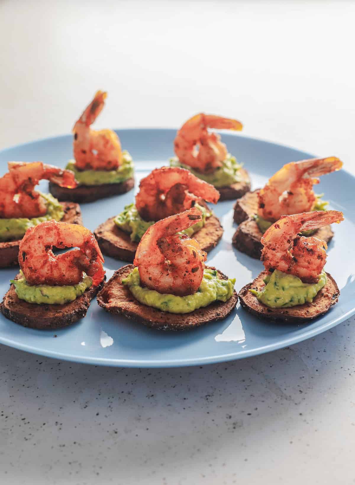 Eight cajun shrimp bites lined up on a blue pan on top of a white surface