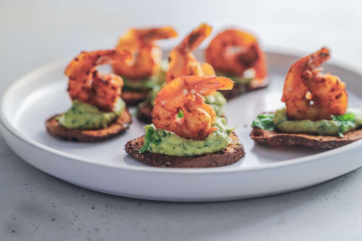 A close-up shot of six cajun shrimp sweet potato bites on a rimmed plate