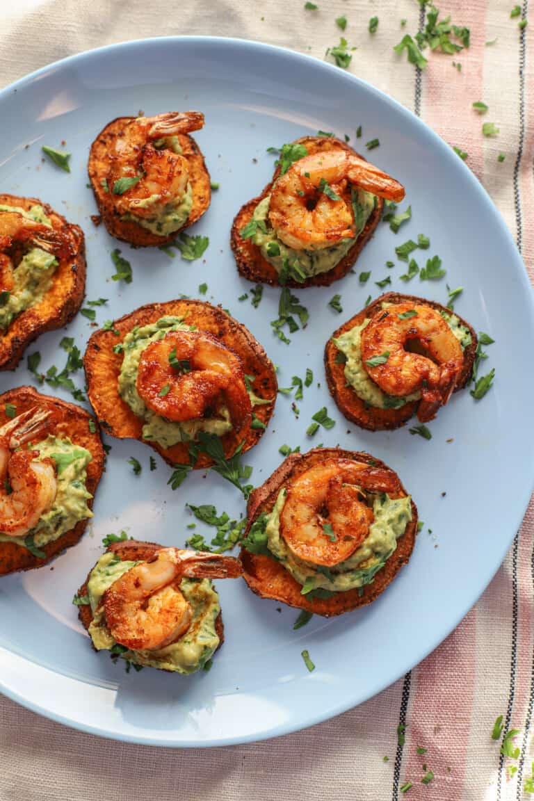 blue plate with small bites made up of sweet potato slices, avocado, and shrimp