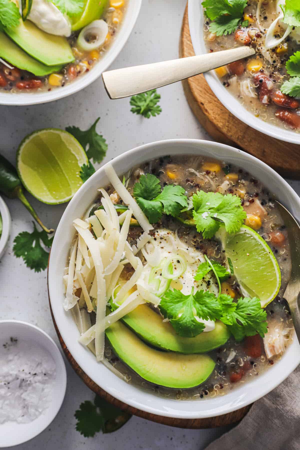 A close-up shot of a bowl of homemade white chicken chili with a lime slice and a dish of salt beside it.