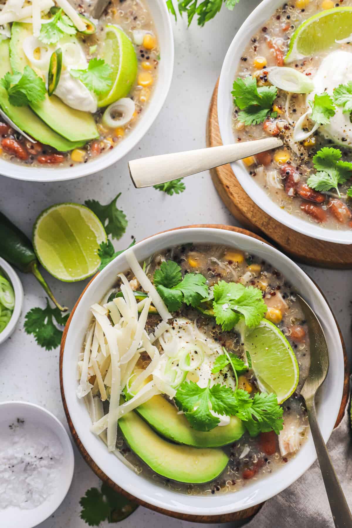 Three servings of crockpot chicken chili in separate bowls on a white countertop.