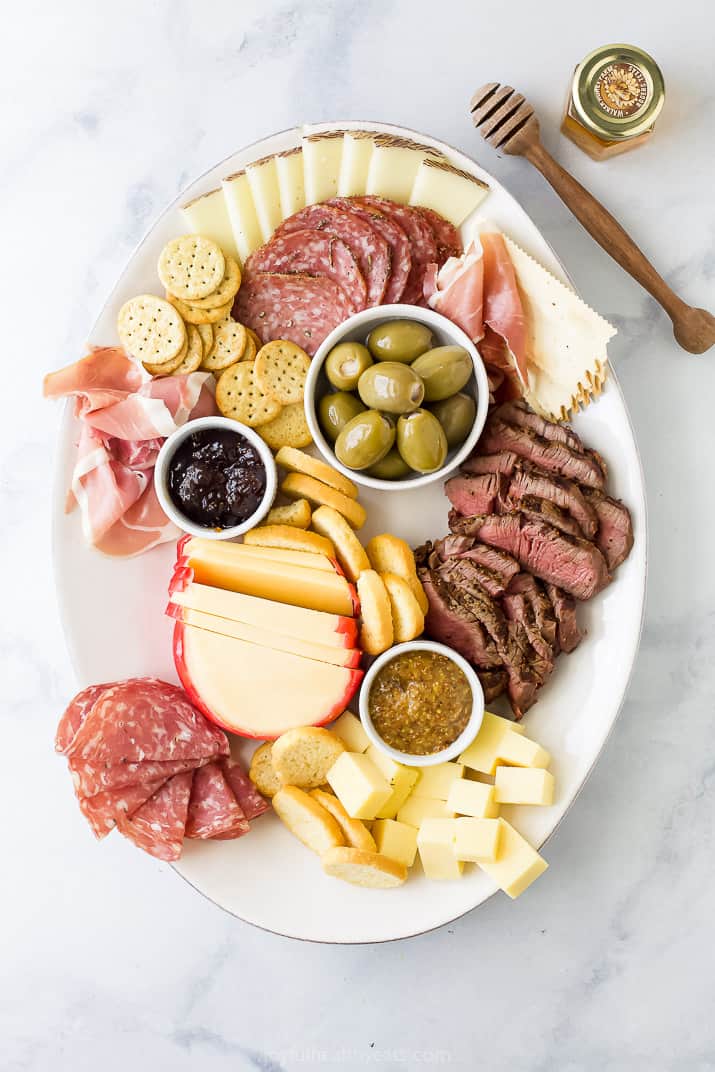 cheese board platter with cheese meats condiments and crackers