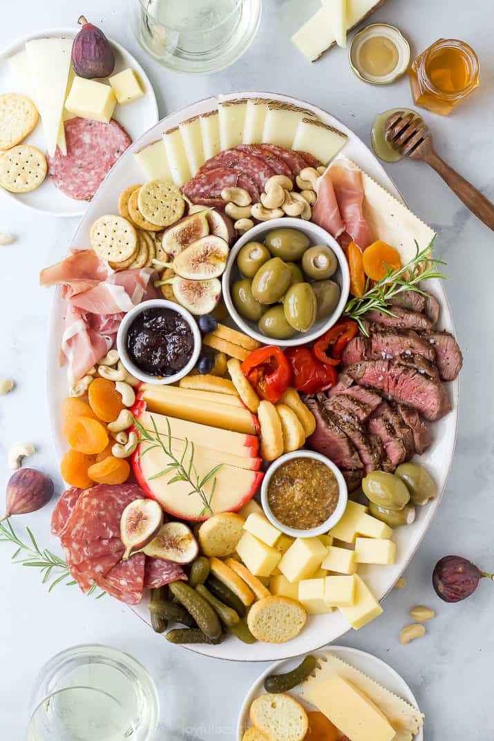 charcuterie board for two with plates and wine surrounding