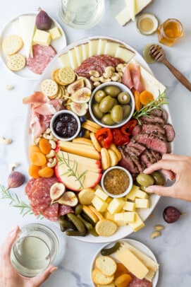 charcuterie board for two with hands grabbing from the board