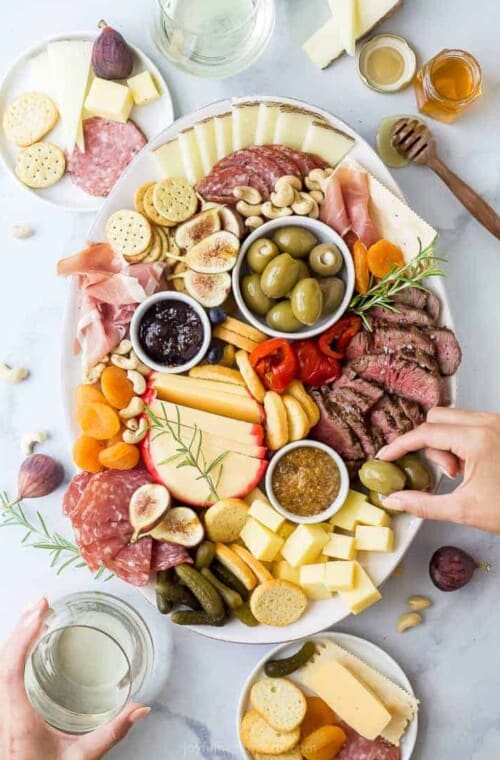 charcuterie board for two with hands grabbing from the board