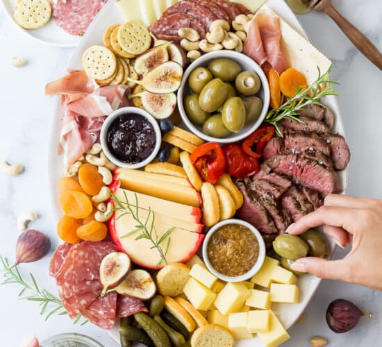 charcuterie board for two with hands grabbing from the board