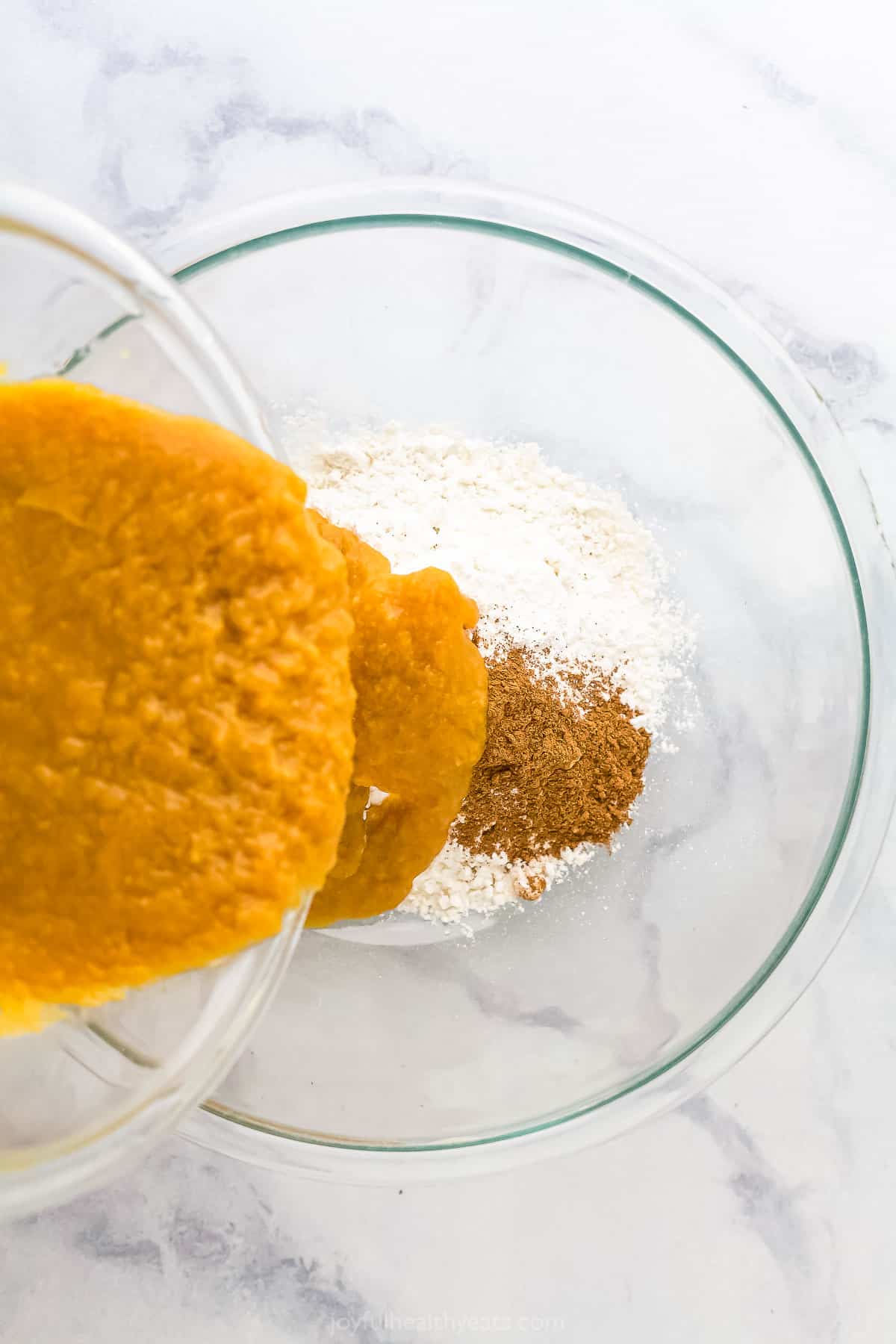 The combined wet ingredients being poured into the bowl of dry ingredients