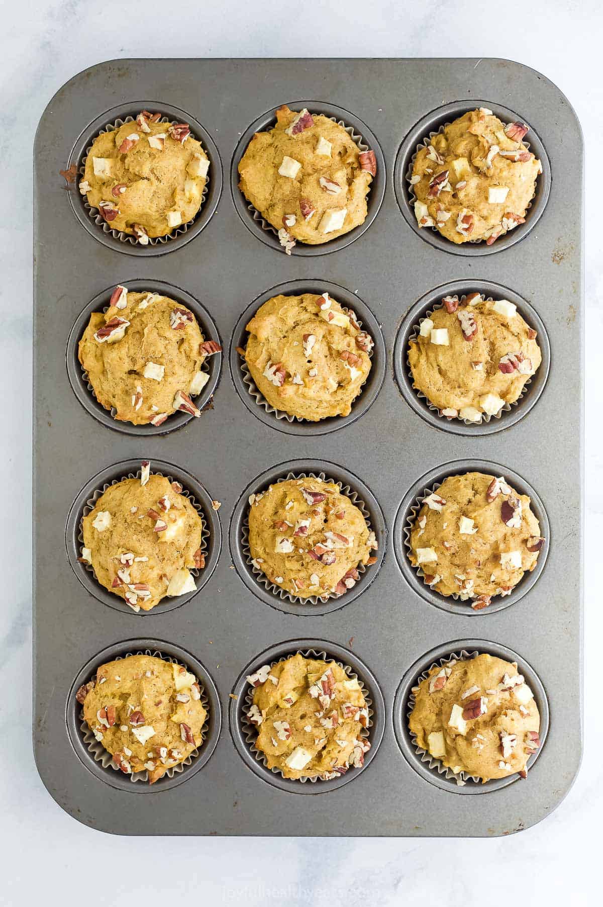 An overhead shot of a twelve-count cupcake tin filled with baked muffins