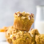 Two apple pecan muffins stacked on top of one another with a glass of milk behind them
