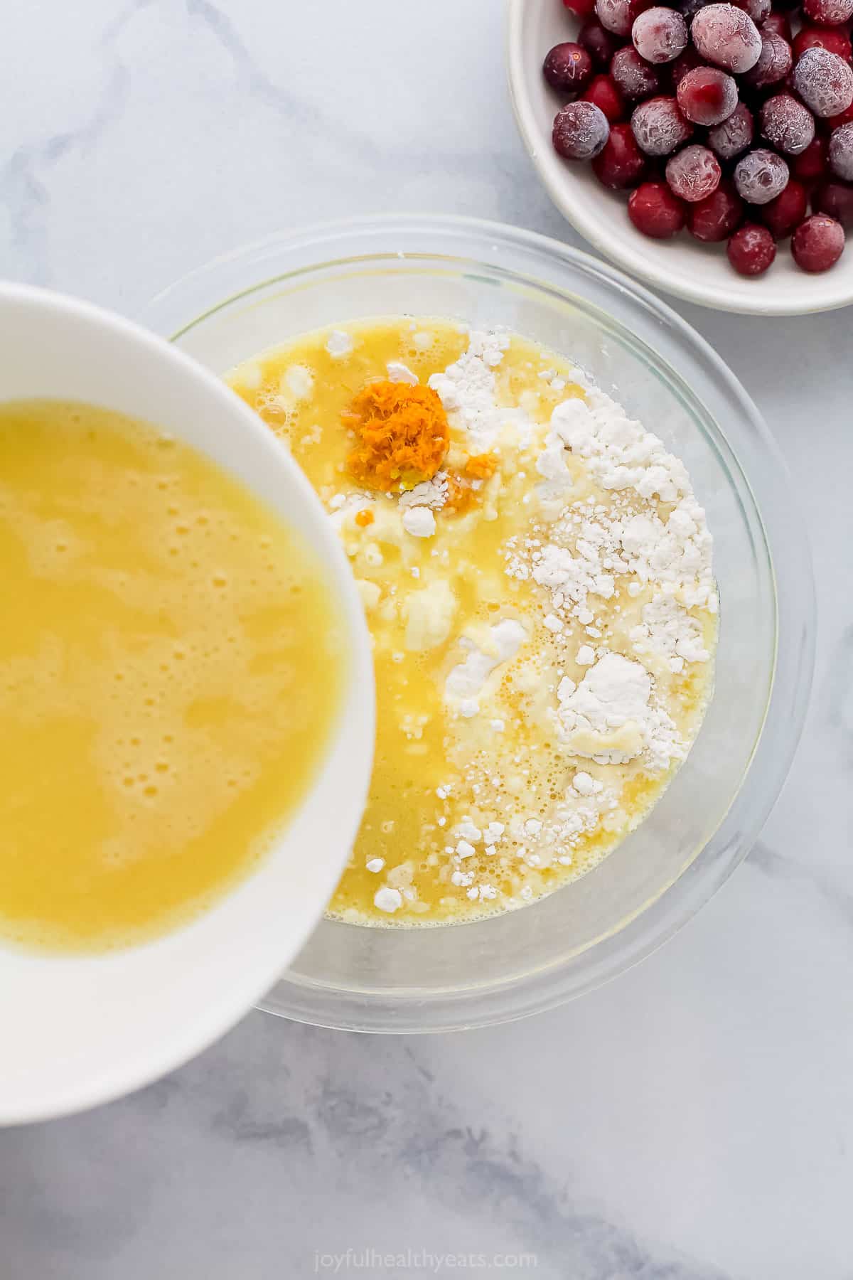 The wet ingredient mixture being poured into the bowl of dry ingredients