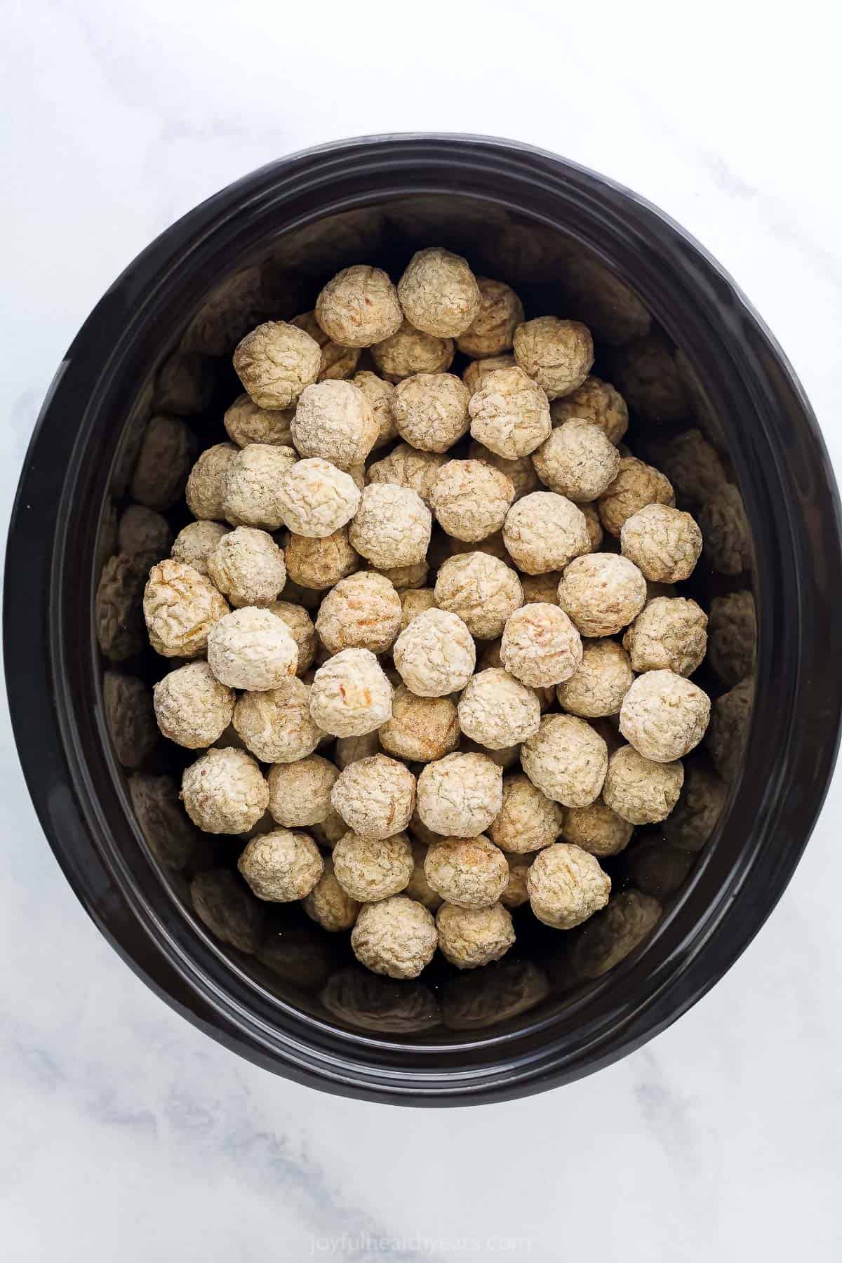 Frozen meatballs inside of the inner pot of a Crockpot