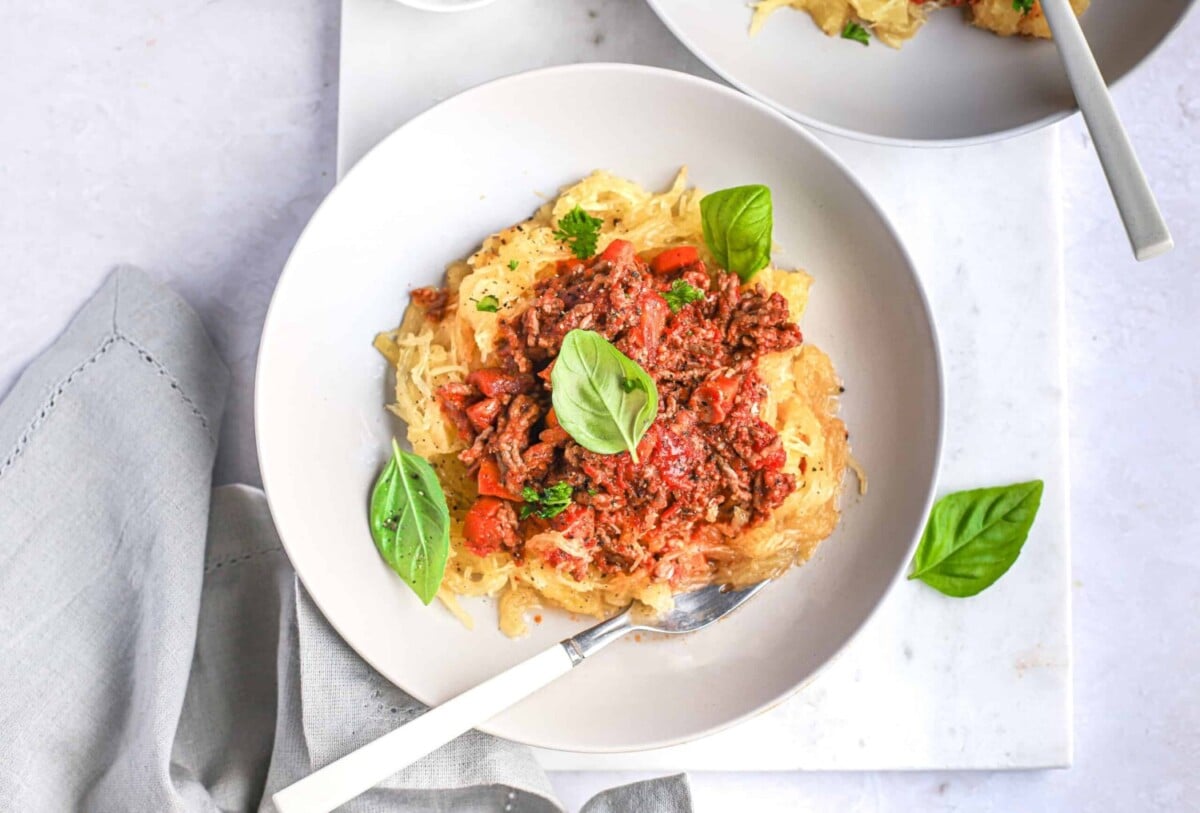 An overhead shot of a bowl of paleo beef bolognese pasta garnished with basil leaves