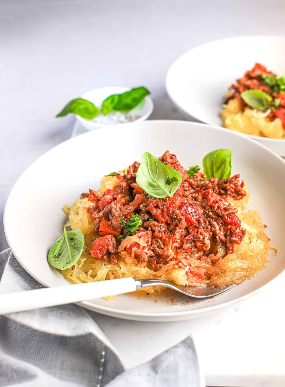 A plate of beef bolognese spaghetti squash pasta with a second serving in the background