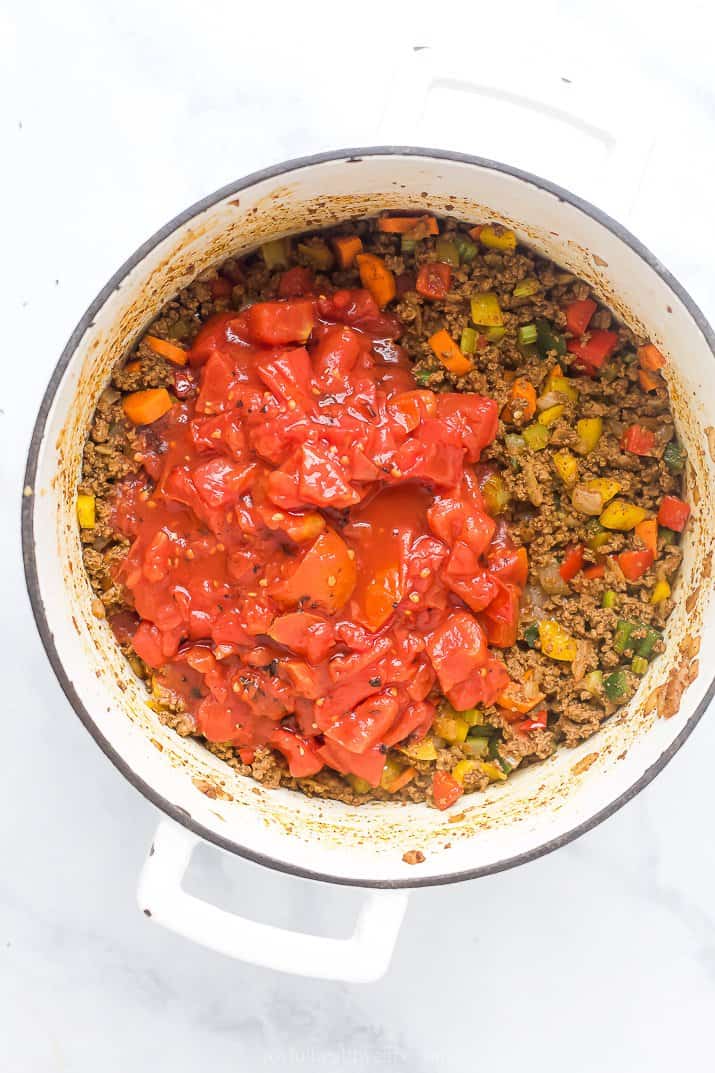 dutch oven filled with beef vegetables and diced tomatoes for chili