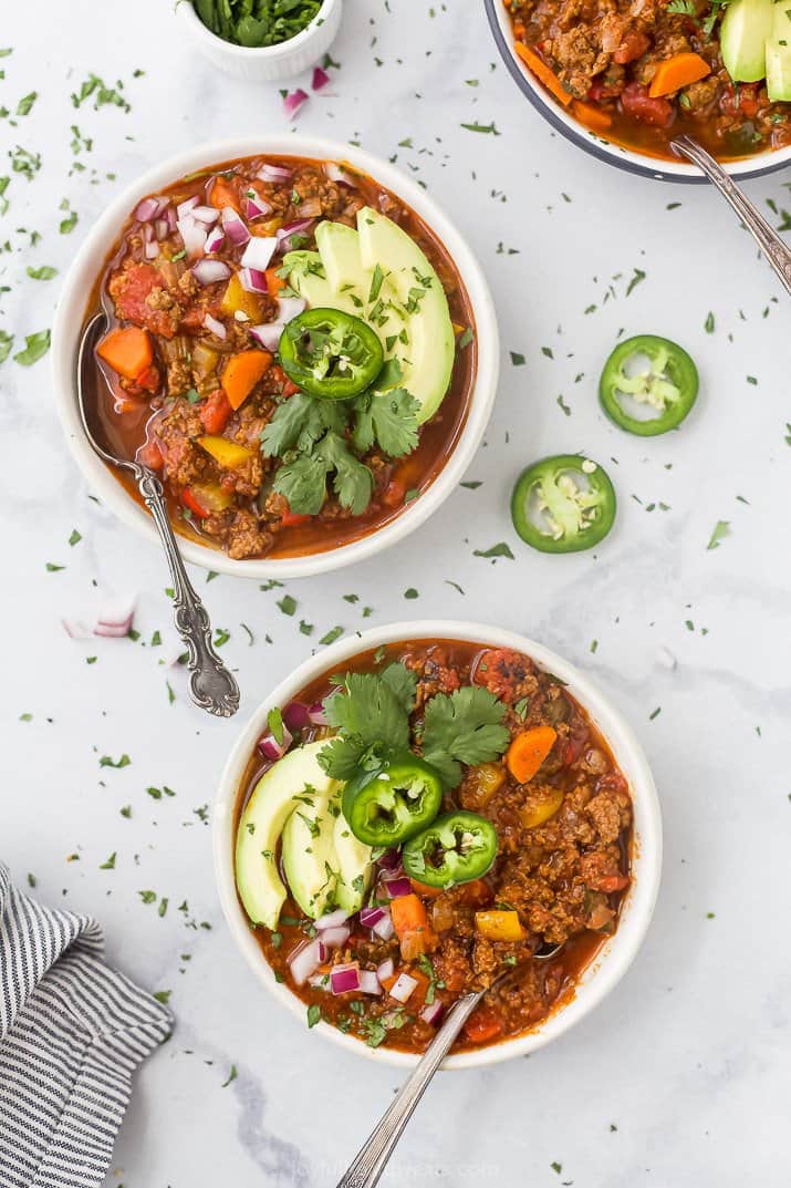 beef chili in a bowl with avocado onion and cilantro