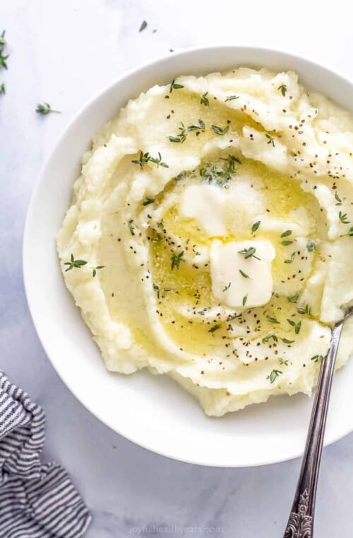 A bowl of mashed cauliflower beside a striped kitchen towel on a countertop