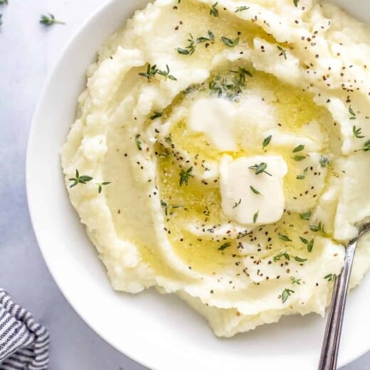 A bowl of mashed cauliflower beside a striped kitchen towel on a countertop